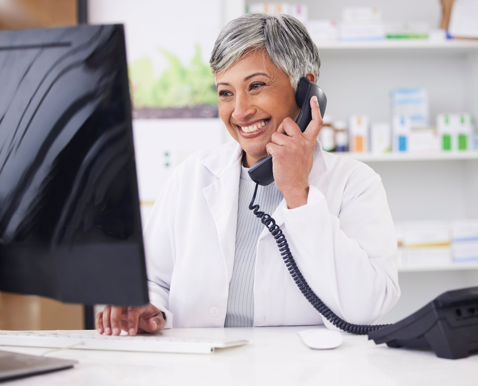 Pharmacist, telephone and computer for prescription with woman in conversation for retail healthcare. Chemist, working and pharmacy on computer with customer service or medicine with telehealth. Pharmacist, telephone and computer for prescription with woman in conversation for retail healthcare. Chemist, working and pharmacy on computer with customer service or medicine with telehealth.
